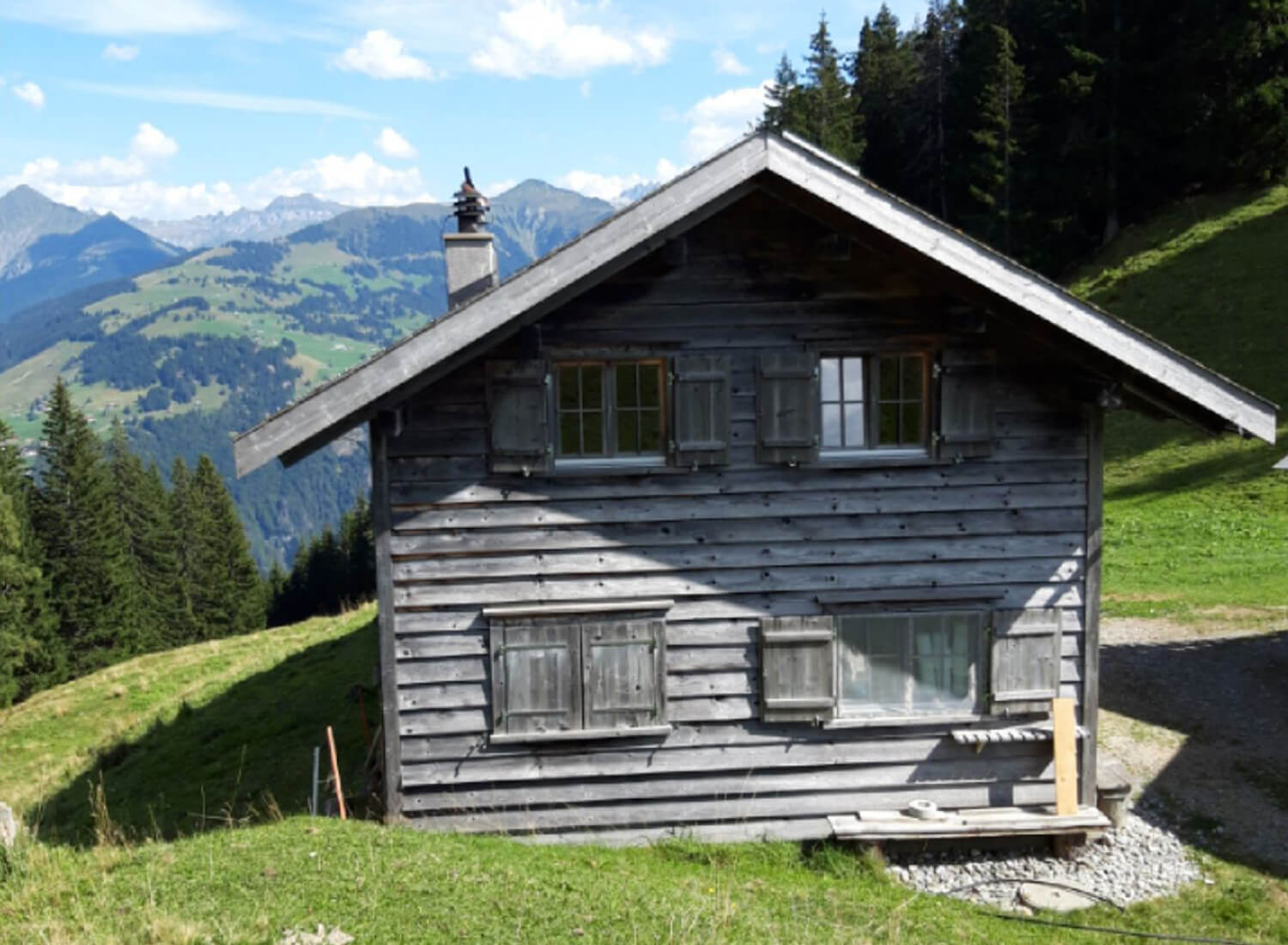 Alphütte aus Holz auf grüner Wiese