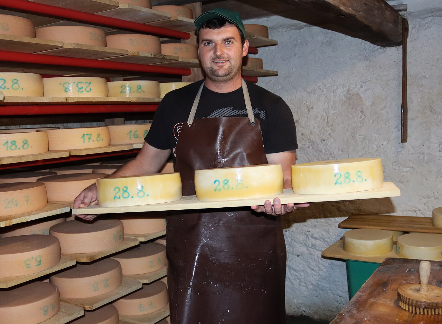 Mann mit einem Brett mit 3 Käselaiben